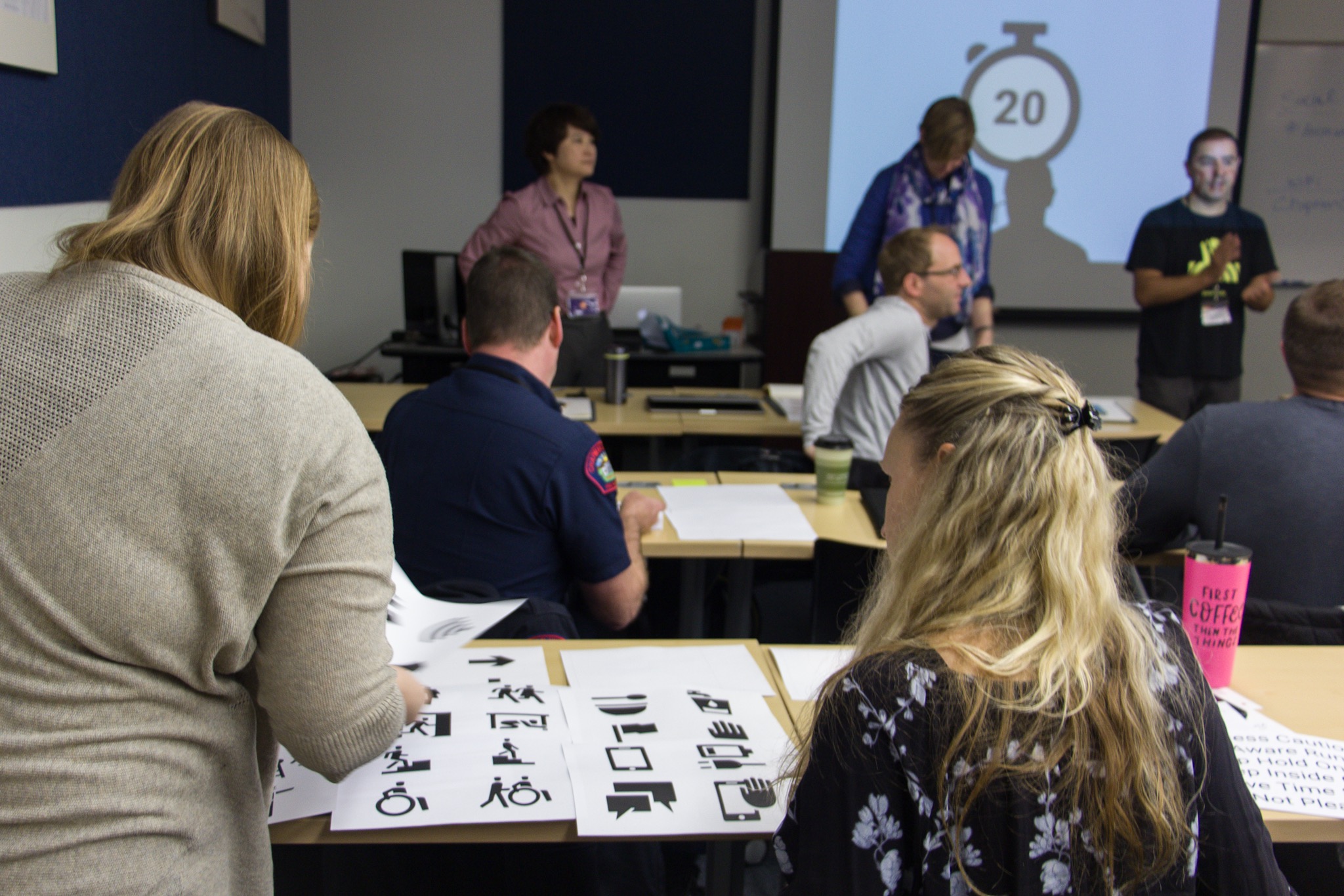 Room full of workshop participants working with visual icons printed on bright yellow paper.