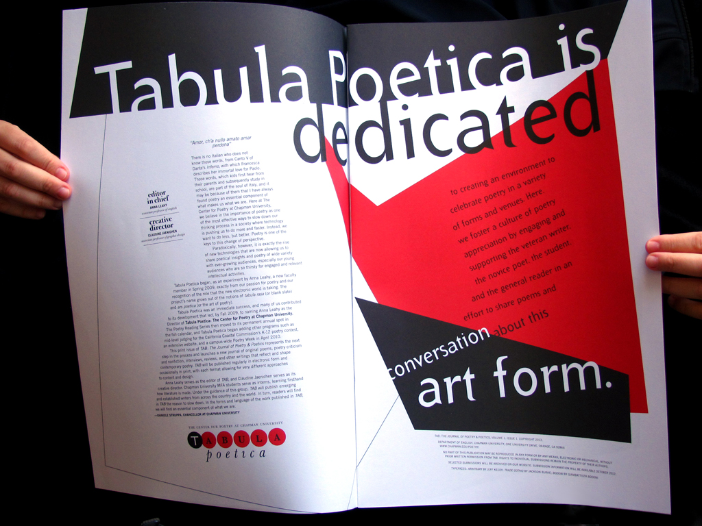 Hands holding pages open to reveal a spread with big shapes of red and black with angled type grid and contrast created by extreme type sizes.